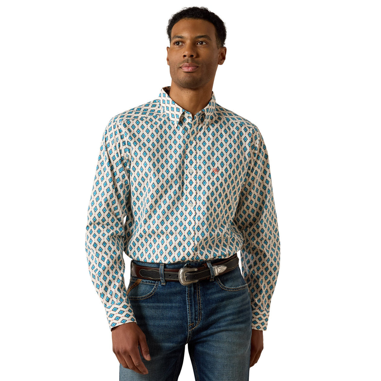 A man wearing a long-sleeve button-down shirt with a blue, white, and beige geometric pattern, paired with blue jeans and a brown belt, against a plain white background.
