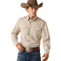 A man wearing a light beige western long-sleeve button-down shirt, blue jeans, a brown cowboy hat, and a brown leather belt with a large silver buckle, posed against a solid white background.