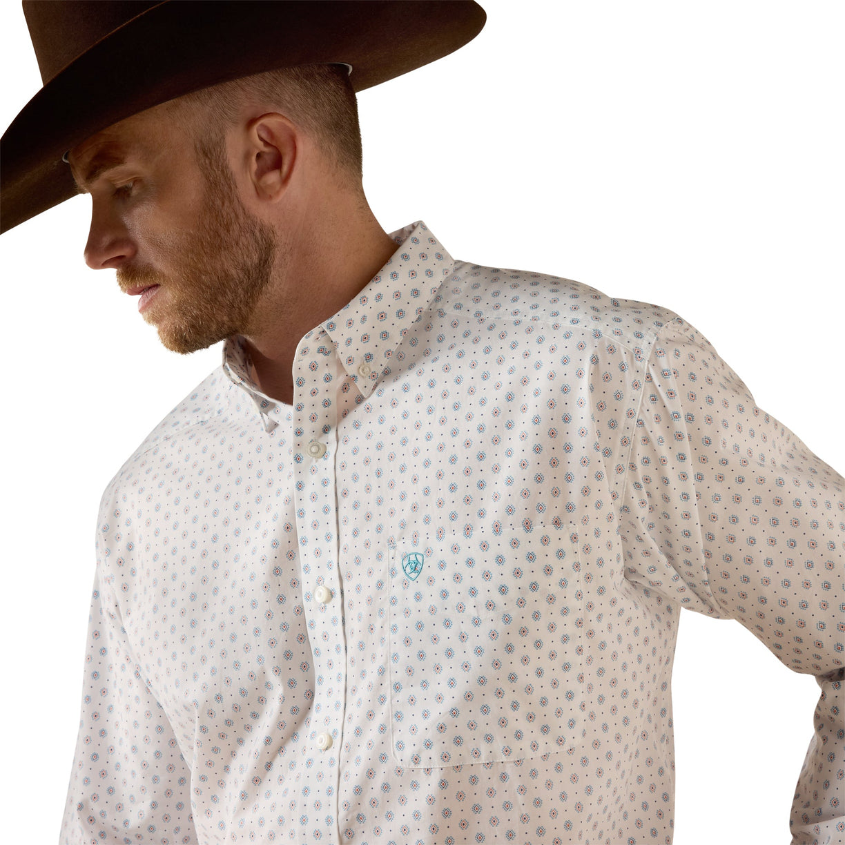 A man wearing a brown cowboy hat and a light-colored western button-down shirt with a small blue geometric pattern, shown in a close-up profile shot against a white background.