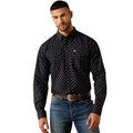 Man wearing a black patterned shirt and blue jeans on a beige background