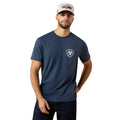 Man wearing a navy blue t-shirt with a logo and a cap on a beige background
