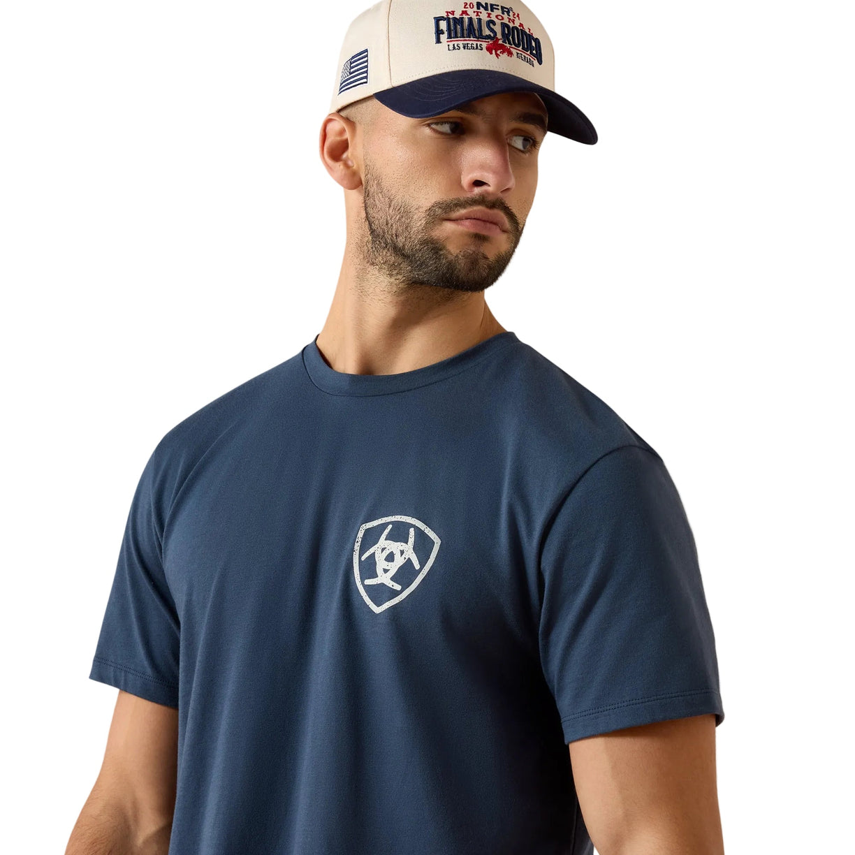 Man wearing a navy blue t-shirt with a logo and a cap on a beige background
