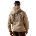 A man viewed from behind wearing a beige pullover hoodie with a large black graphic on the back featuring the word 'WORKHOGS' and an illustration of a boar. He is also wearing a black baseball cap and brown pants, set against a plain white background.