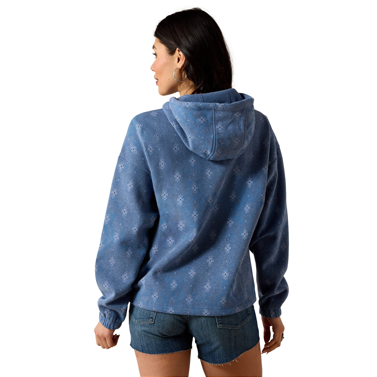 A woman shown from the back wearing a blue hooded sweatshirt with a subtle white allover pattern, paired with denim shorts, against a plain white background.