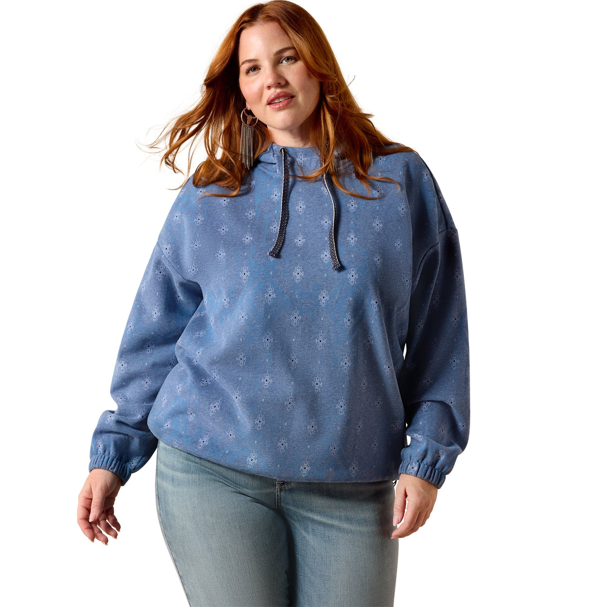 A woman modeling a dusty blue hooded sweatshirt with a subtle white snowflake pattern, paired with light-wash blue jeans against a solid white background.