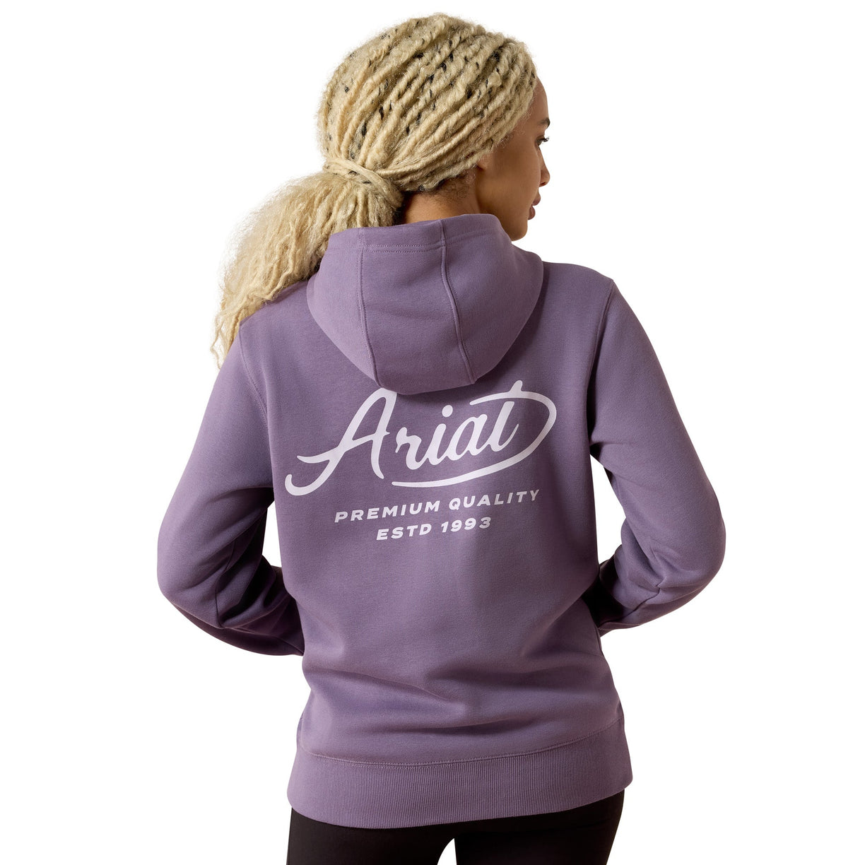 A woman with blonde braided hair is shown from the back wearing a lavender-purple hoodie with a white graphic print that reads 'Ariat Premium Quality Estd 1993'.
