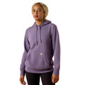 A woman wearing a lavender purple pullover hoodie with a drawstring hood and kangaroo pocket, paired with black pants, against a plain white background.