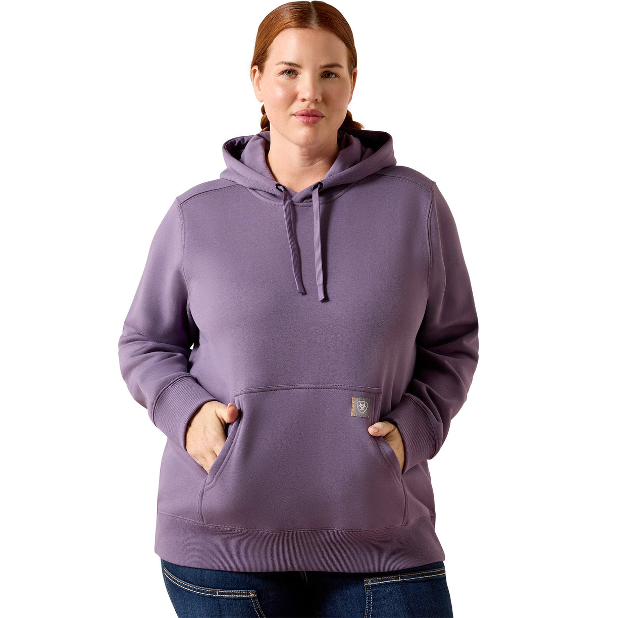 A woman wearing a dusty purple pullover hoodie with drawstrings and a kangaroo pocket, paired with blue jeans, against a plain white background.
