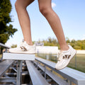 White sneakers with animal print details on a person standing on bleachers outdoors.