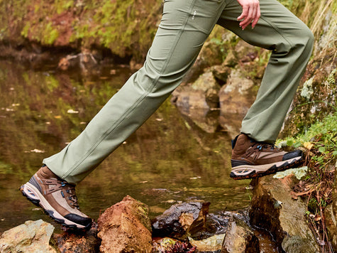 Hiker wearing new Ariat Traverse Hiking Boots and Pants crossing a creek.