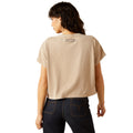 Person wearing a beige t-shirt with text on the back, standing against a white background