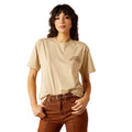 Person wearing a beige t-shirt with text and brown pants on a white background