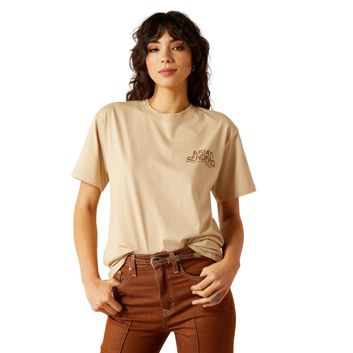 Person wearing a beige t-shirt with text and brown pants on a white background