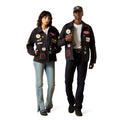 Two people wearing black jackets with various patches on a white background
