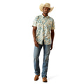 Man wearing a patterned shirt, jeans, and a cowboy hat on a white background