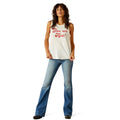 Woman wearing a white tank top with red text and blue jeans on a white background
