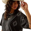 Woman wearing a black patterned top and straw hat on a white background