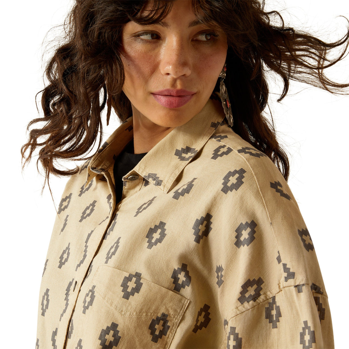 Woman wearing a beige patterned shirt with a neutral background
