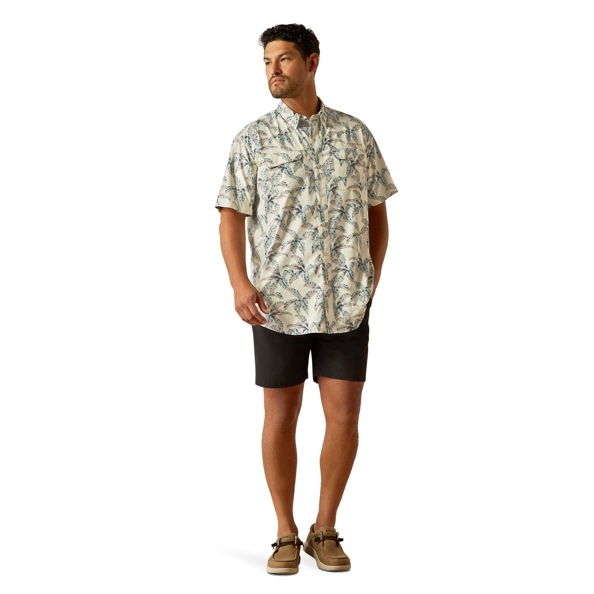 Man wearing a patterned shirt and black shorts on a white background