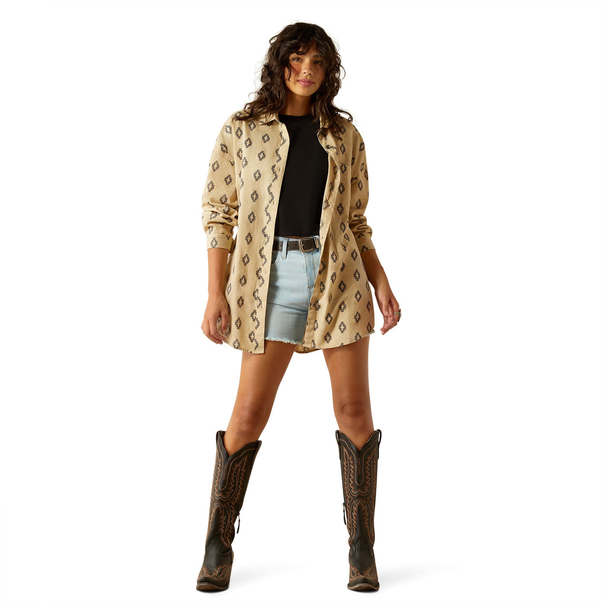 Woman wearing a patterned shirt, denim shorts, and cowboy boots on a white background