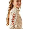 Girl wearing a patterned shirt with visible branding on a white background