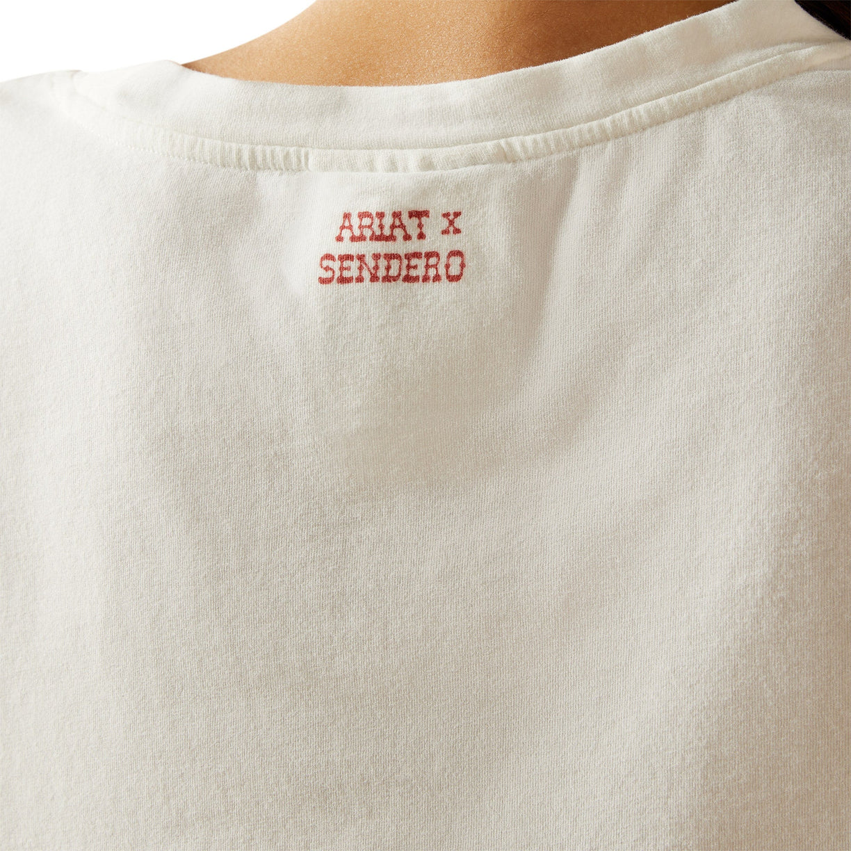 Close-up of a white shirt with 'Ariat x Sendero' text on the chest.