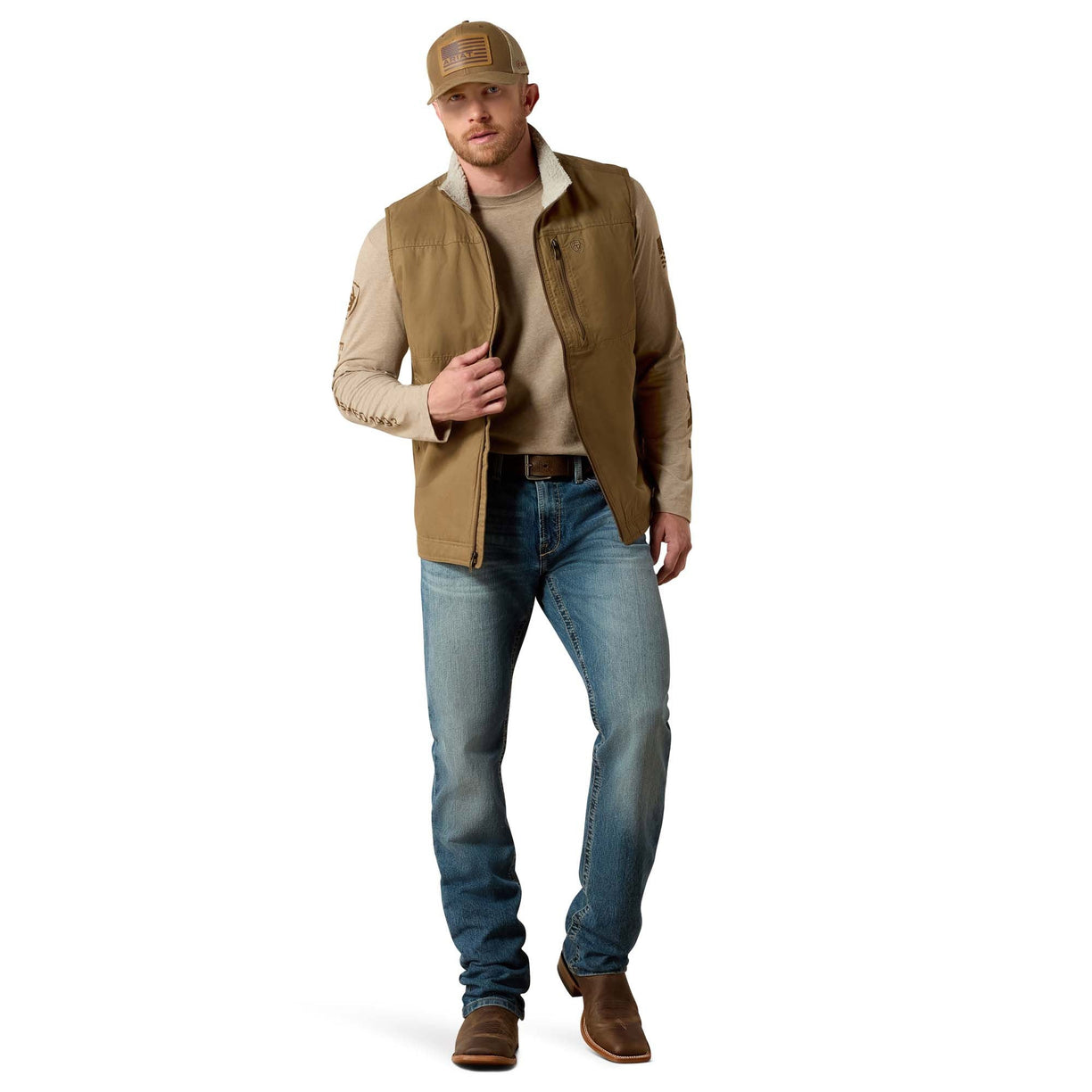 Man wearing a brown vest, beige shirt, blue jeans, and brown boots on a white background